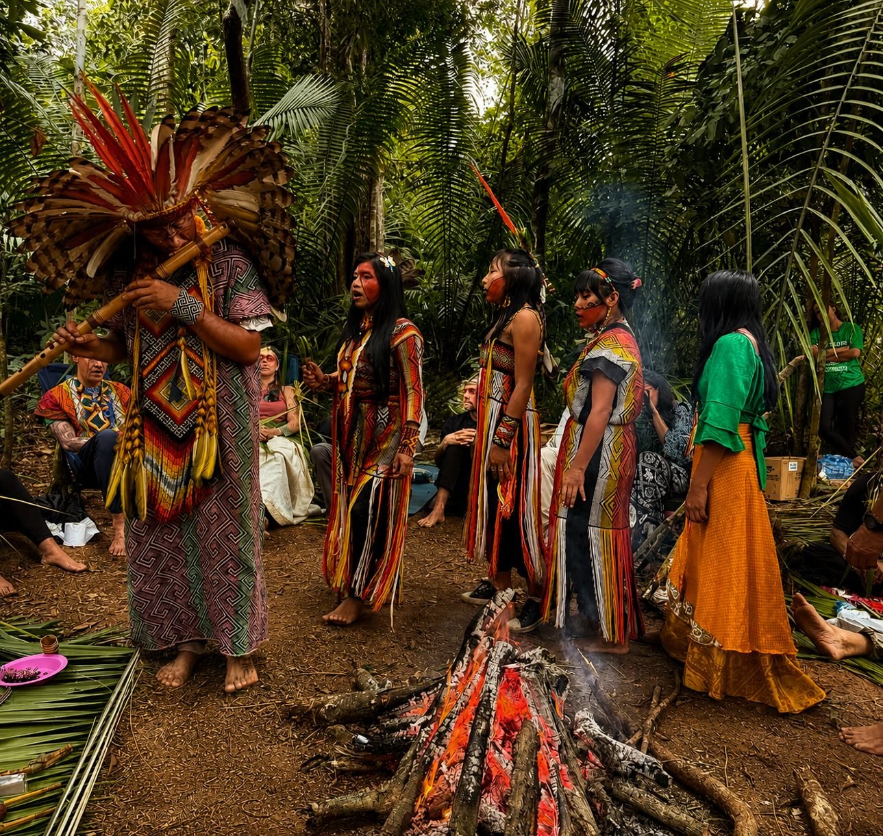 Roda Huni Kuin na floresta, com pessoas em vestes coloridas reunidas ao redor do fogo