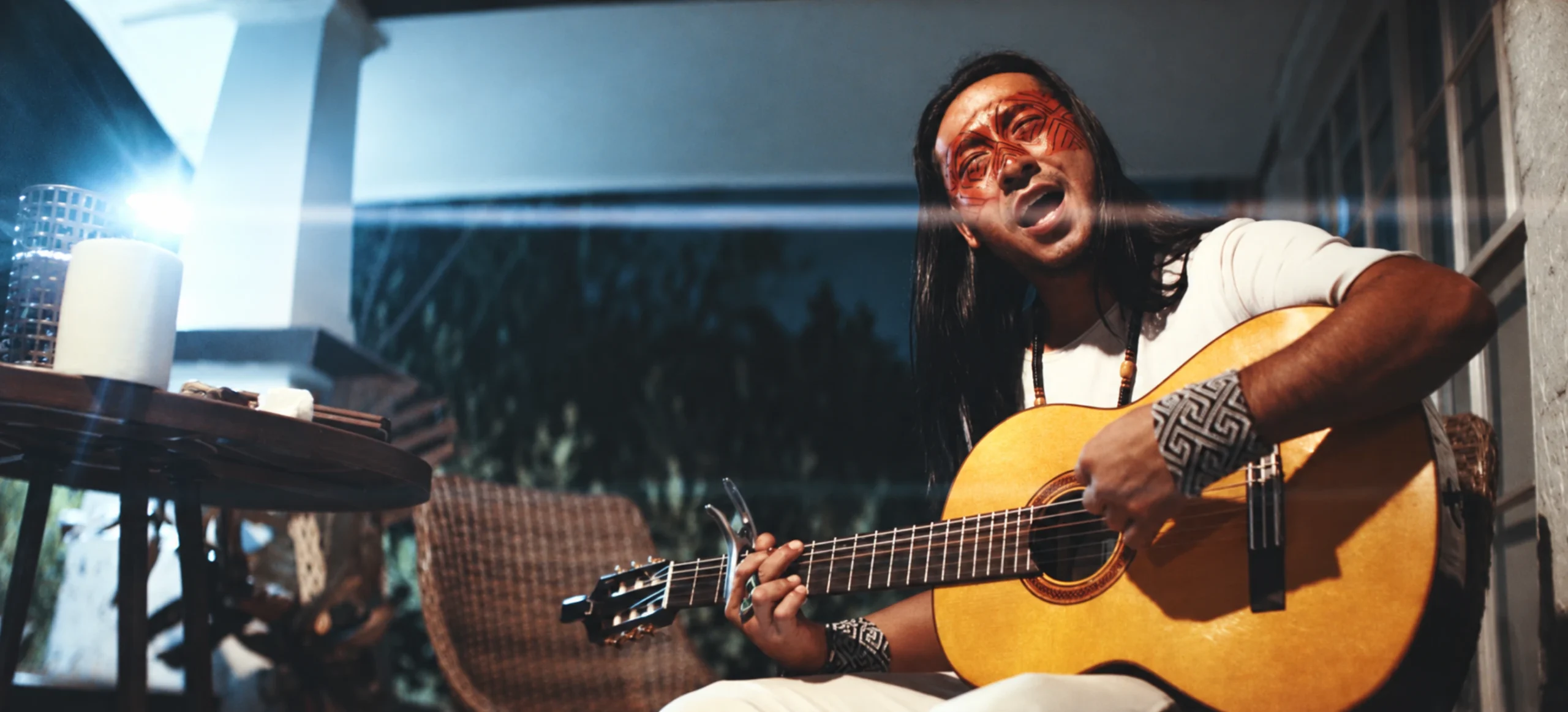 Mapu Huni Kuin canta de olhos fechados enquanto toca violão